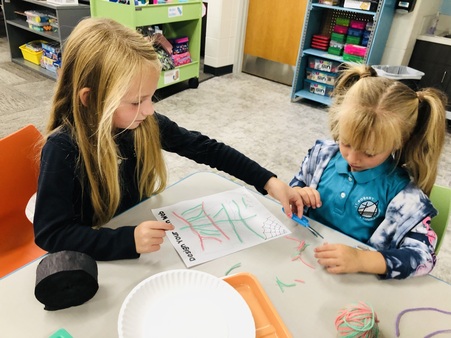 First grade and young 5 students planning and building a spider web.